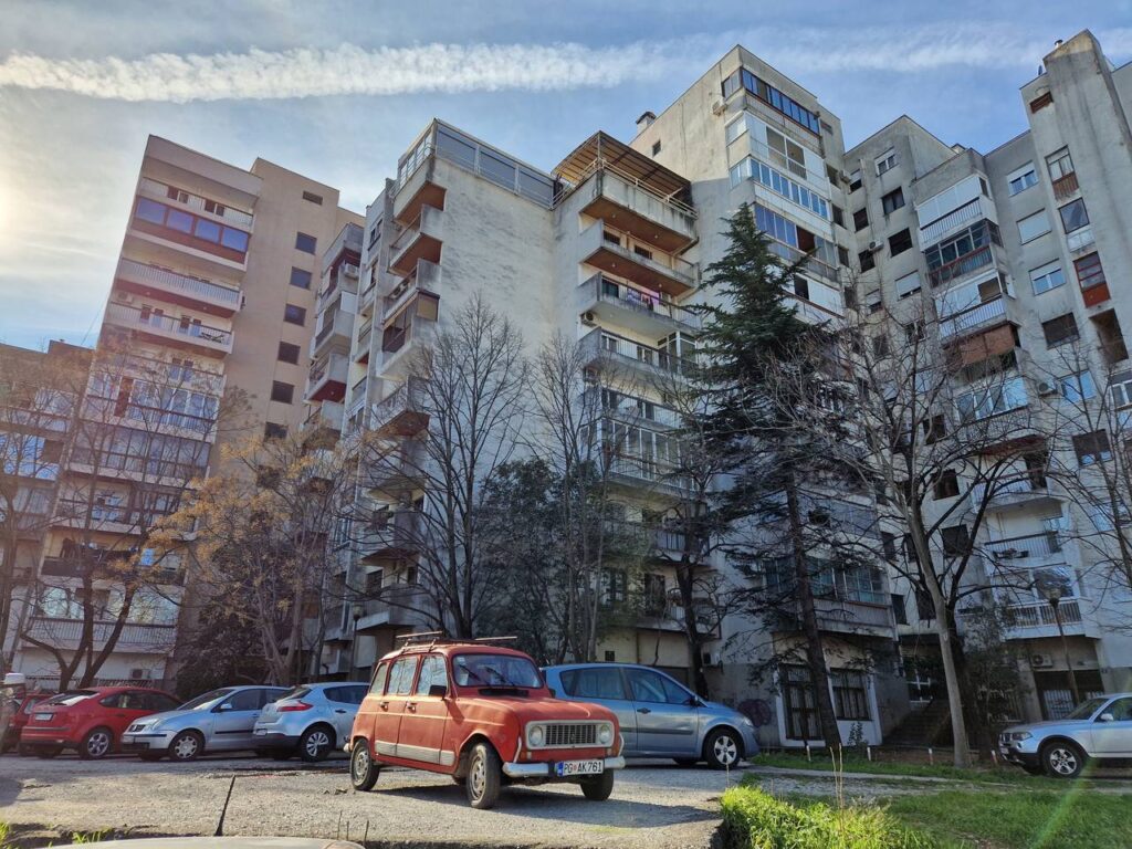 Από τις αγαπημένες μου φωτογραφίες στην Ποντγκόριτσα! Συγκρότημα παλιών "σοβιετικών" πολυκατοικιών με ένα παλιό κόκκινο αμάξι μπροστά.